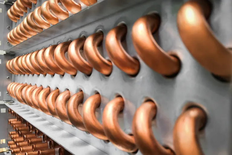 Row of copper tubes from an air conditioning condenser in close-up