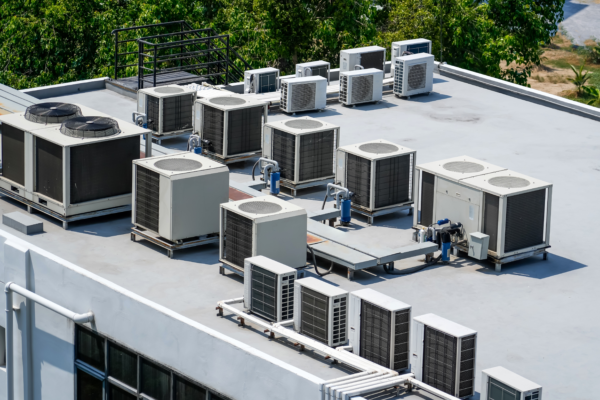 Cluster of air conditioners and condenser units installed on the flat roof of a building